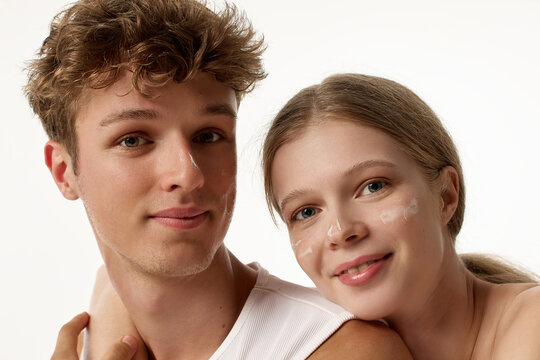 Soft close-up portrait of smiling young couple with clean healthy complexions. Concept of face symmetry beauty, close connection portrait, minimal cosmetic campaign.