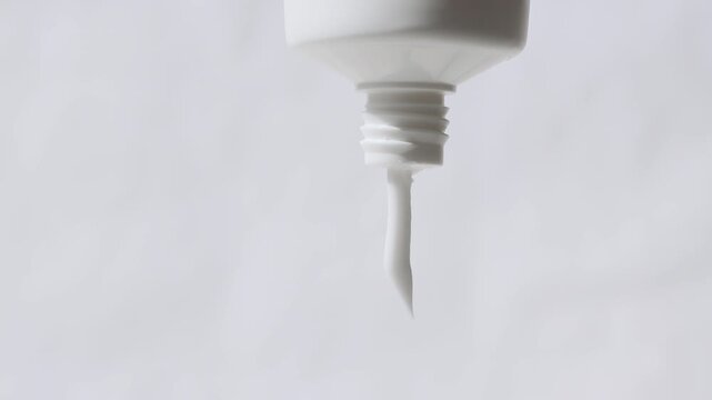 A close-up of a face and hand cream packaging with cosmetic texture flowing out.