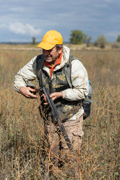 A hunter with a gun in camouflage clothing. A senior man with a gun, medium shot, searching for game.