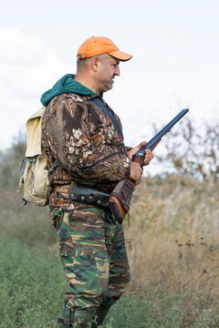 A hunter with a gun in camouflage clothing. A senior man with a gun, medium shot, searching for game.