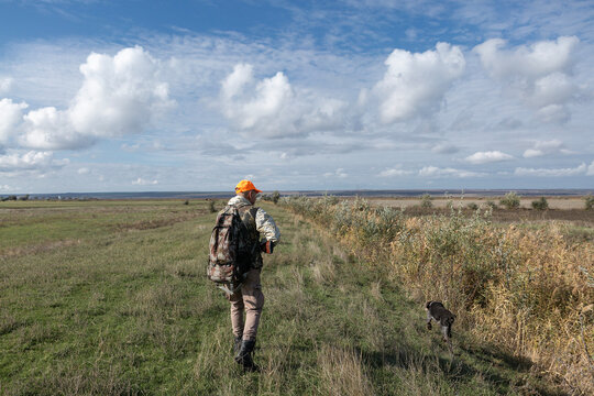 A hunter with a gun in camouflage clothing. A gentleman with a gun, medium shot, unrecognizable.