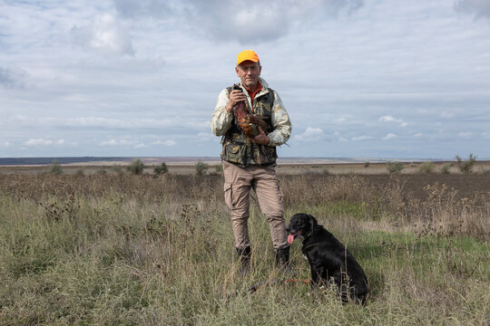 A hunter holds a pheasant in his hands. A successful hunt, a trophy game.