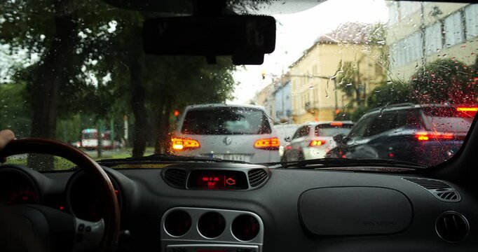 Car sitting at a stop light in rainy weather, interior view with shallow depth of field and blurry background traffic