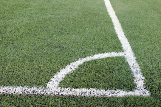 close up of a soccer field corner showing white boundary lines on green grass with precise markings and outdoor sports setting