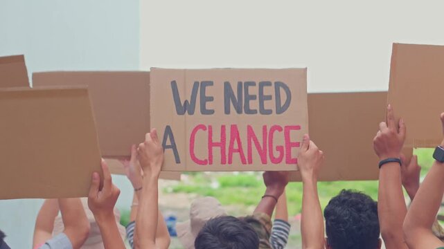 Protesters holding cardboard signs with we need a change slogan at public demonstration.