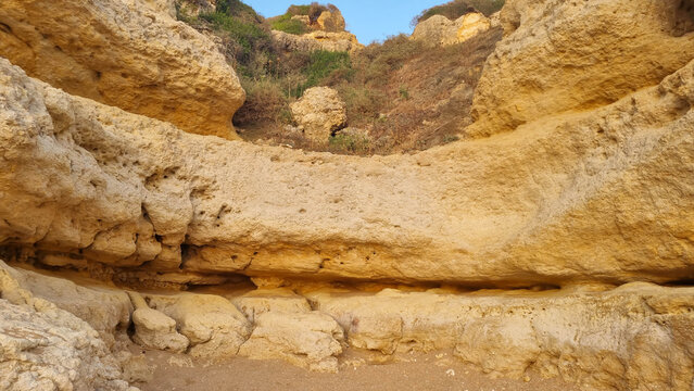 Weathered limestone cliffs with natural caves under clear blue sky on Mediterranean coast