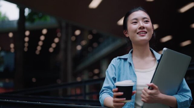 Young Female University Student Holding Coffee Cup and Laptop Outdoors on Campus