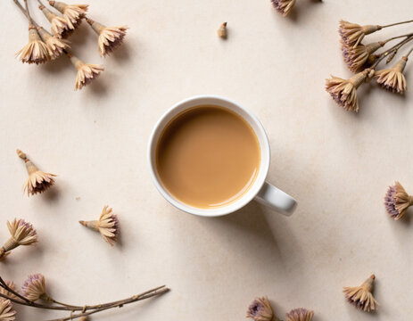 Top View Flat Lay of Milk Coffee Cup surrounded by Dried Botanical Flowers on Neutral Surface