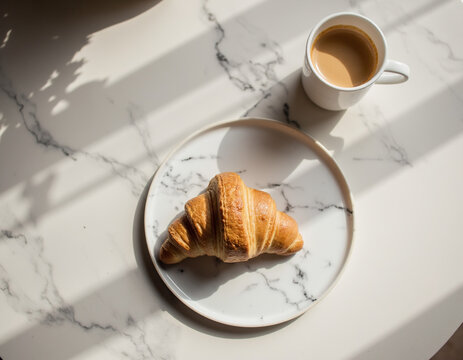 Top View Flat Lay of Freshly Baked Butter Croissant on Marble Plate with Cup of Coffee in Soft Sunlight