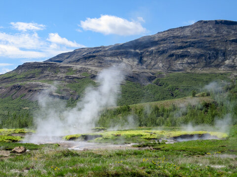 Steam rising from hot springs and geysers in an active geothermal area, showing an extreme natural environmental landscape in the Haukadalur valley of Iceland