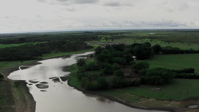 Expansive aerial perspective showing a muddy river winding through the vast, green plains of the Colombian Llanos, a remote and biodiverse savanna