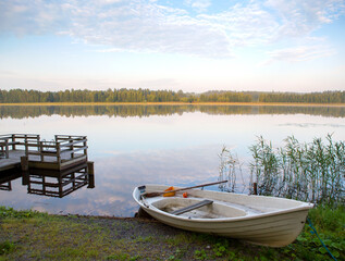 Obraz premium Small pier on a lake shore. Finnish relaxation moment during the holidays. Sunny and calm weather. Place for swimming and fishing.