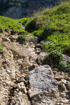 Clear mountain stream flowing over rocks beside a narrow hiking trail on a green slope in Azerbaijan. Scenic natural landscape representing trekking, adventure travel, freshwater and outdoor explorati