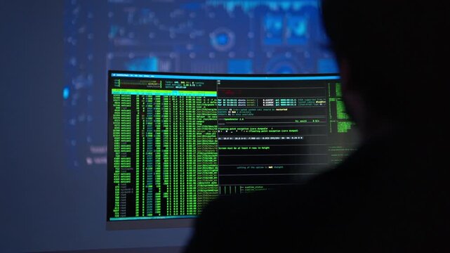 Software developer monitoring artificial intelligence systems and programming code on multiple displays in a modern technology workspace