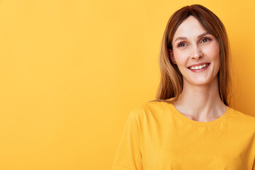 Fototapeta premium Bright studio portrait of a smiling woman in a yellow shirt, standing against a vivid yellow background, conveying warmth, positivity and casual style.