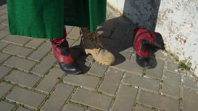 Boots footwear mismatch person wearing green dress changes from mismatched military and fashion boots to matching pair of red boots on pavement