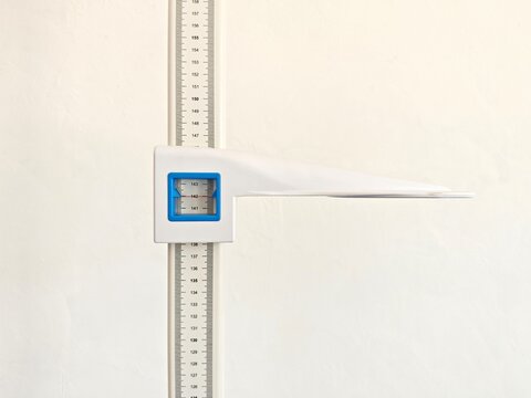 Wall-mounted height measuring scale with adjustable headpiece used for measuring human height in clinics, schools, hospitals, or health facilities, isolated on a clean white background