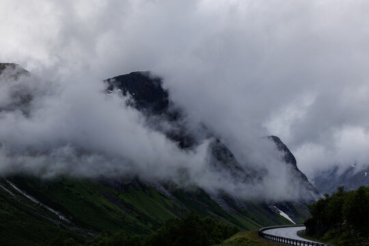 Mountain road disappearing into low clouds in Norway