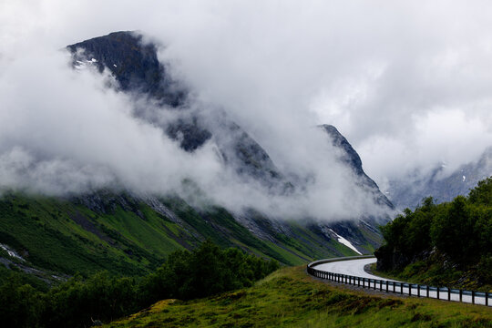 Mountain road disappearing into low clouds in Norway