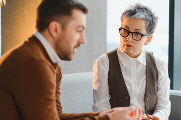Man communicating with female psychologist during therapy session