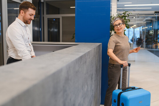 Woman checking in hotel lobby with luggage