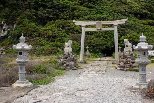 Mother and Son go through Torii gate and along stone lanterns to the entrance to Ominato Shrine on Oshima Island, Fukui, Japan