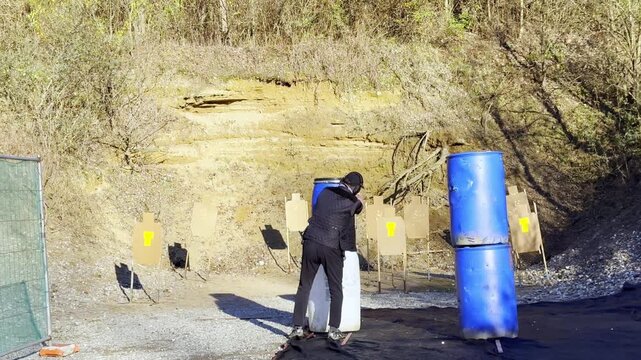 Elegant Man Training Dynamic Shooting IDPA in an Outdoor Shooting Range with a Modern Handgun in a Sunny Day in Switzerland. (Slow Motion)