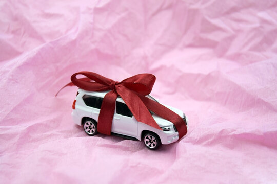 A gift car wrapped in ribbon bow on the pink background.