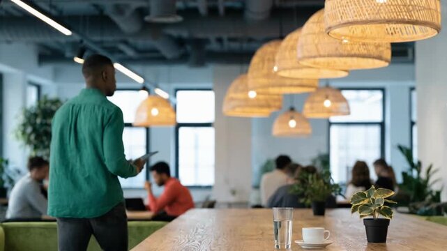 Medium view of an employee holding a tablet showing debt summary with surrounding office space softly out of focus.