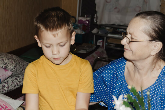 gentle grandmother blue top patiently shows her young grandson how sew piece fabric focused collaboration capturing warmth family learning passing traditions quiet joy creating something together