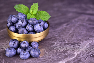 Fresh blueberries in a metal bowl on a black background. Copy space.  © Olivka888