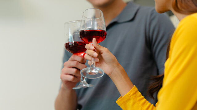 happy Asian couple drinking red wine together in kitchen room