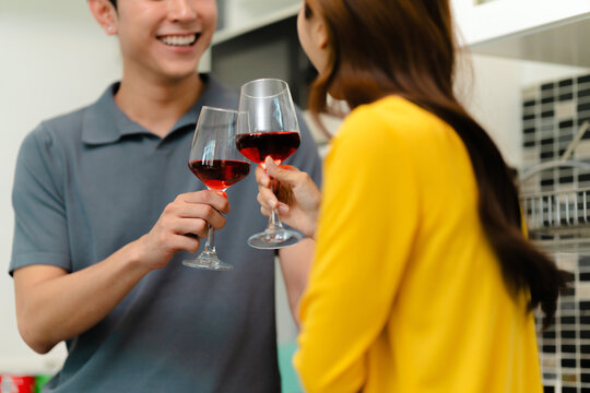 happy Asian couple drinking red wine together in kitchen room