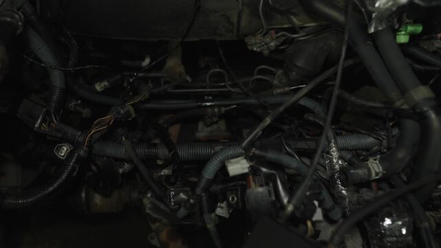 A complex view of a car engine bay filled with wires, hoses, and mechanical components.