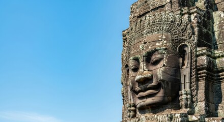 Obraz premium Ancient stone face sculpture at bayon temple in angkor wat cambodia under a clear blue sky