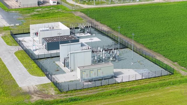 Aerial view of an electrical power substation with transformers, high-voltage cables, and grid infrastructure. Industrial energy distribution facility.