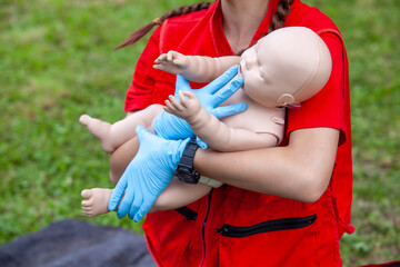 Paramedic in Red Uniform Wearing Blue Gloves Practices Infant CPR on Realistic Baby Training...