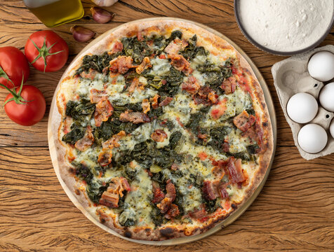 Endive, bacon and mozzarela pizza over wooden table with ingredients