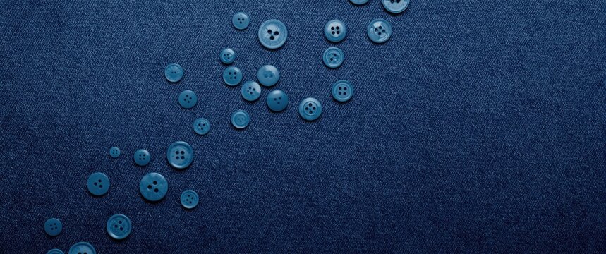 Blue Buttons Dispersed on Dark Denim Background with Textured Surface