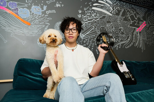 Young Asian man enjoying creative moments with his dog in a vibrant recording studio