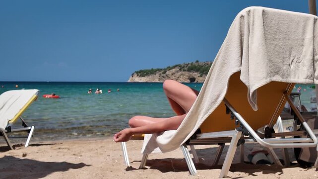 Young woman relaxes on a sun lounger on a sunny beach by the crystal clear sea., a beachgoer resting on a deckchair with a cigarette in his hand.
