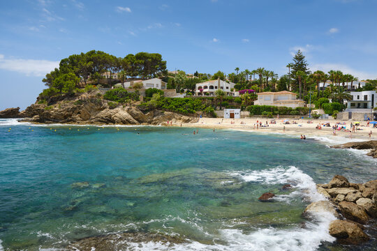Cala de la Fustera beach with clear turquoise Mediterranean water, rocky coastline, coastal villas and summer visitors on the Benissa coast near Calpe, Spain