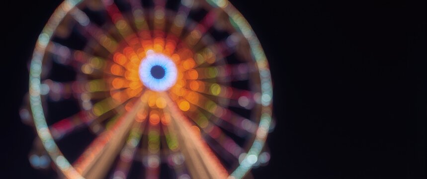 Illuminated Ferris Wheel at Night with Colorful Bokeh Lights