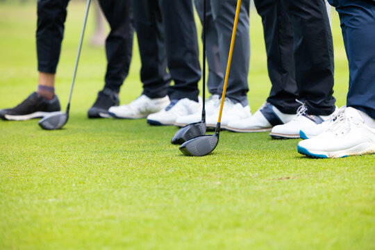 Closeup driver Golf club, Black ground is Golfer team together with white shoes, shot of golf players at the putting green. professional golfer playing golf on field.