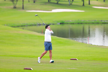 Obraz premium professional golfer on field. Asian Man Golfer Hitting Golf Shot on golf Course. teeing off golf ball. Sport outdoor