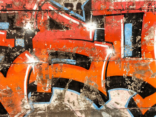 Vibrant orange and blue graffiti lettering with peeling paint on weathered wooden planks © Aryo