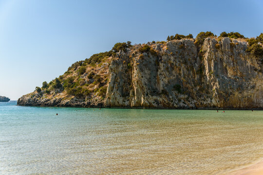 Rugged limestone cliff headland above emerald water at Voidokilia beach, Messenia, Peloponnese, Greece