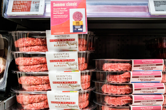 Close-Up Shot Of Packages Of Essential Waitrose Higher Welfare Beef Burgers Neatly Stacked On A Supermarket Refrigerator Shelf, No People