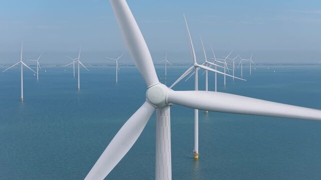 Aerial drone view of an offshore wind farm station in the sea. Modern renewable energy turbines generating clean electricity and sustainable alternative power in the ocean.