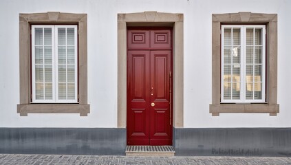 Fototapeta premium Red Door Framed by Windows on a White Wall in Minimalist Style